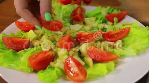 女性手把樱桃番茄片放在一盘沙拉里时光飞逝视频的预览图