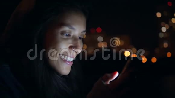 迷人的微笑女孩在夜城的街道上使用手机慢动作4K莫斯科俄罗斯视频的预览图