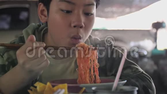 小亚洲男孩在餐馆用筷子吃面条的慢动作视频的预览图