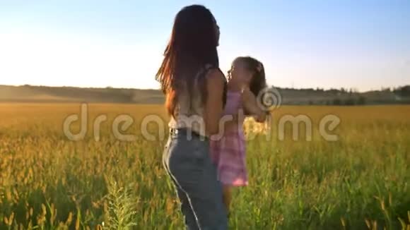 母亲的剪影抱起女儿夏天和孩子一起在田野散步家庭观念视频的预览图
