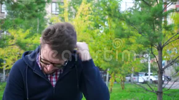 坐在公园里沮丧的中年男子胡子和眼镜慢点视频的预览图