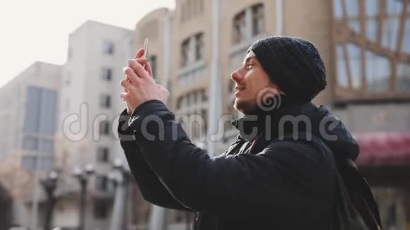 城市街头的男子游客拍摄建筑物视频的预览图