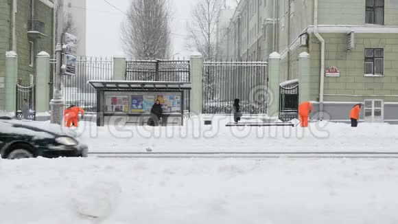 工人们在冬天从人行道上扫雪在暴风雪中清扫人行道视频的预览图