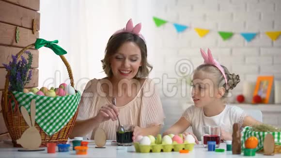 小女孩兴奋地看着妈妈用绿色食物染色蘸蛋复活节视频的预览图