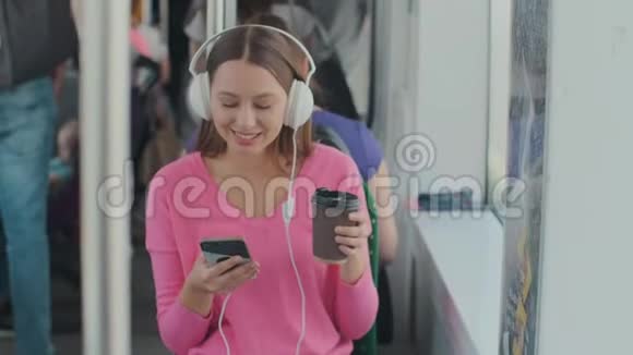 坐在公共交通工具上享受旅行的年轻女乘客戴着耳机坐在现代有轨电车的车窗旁视频的预览图