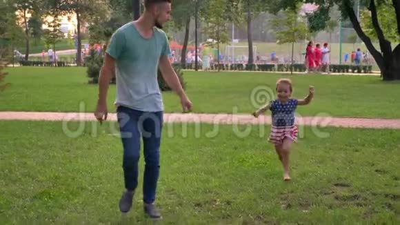 年轻的一家人夏天坐在公园里女儿和爸爸跑向妈妈玩概念视频的预览图