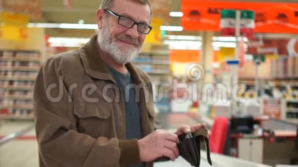一位在超市里手里拿着钱包的老人的肖像养老金领取者微笑视频的预览图
