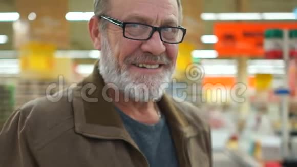 一个戴着黑边眼镜的灰胡子男子的肖像张开的微笑看得见的牙齿直视的蓝眼睛视频的预览图