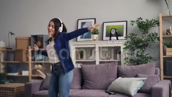 年轻女子听音乐唱歌跳舞在家跳在沙发上视频的预览图