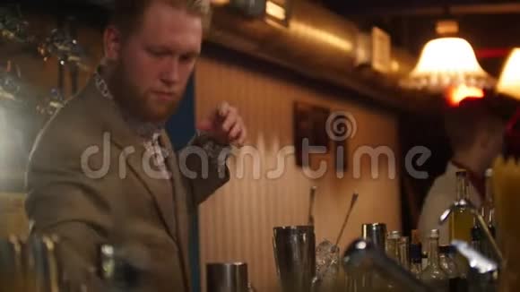 年轻的专业酒保在酒吧里倒着一杯酒里面灯光柔和视频的预览图