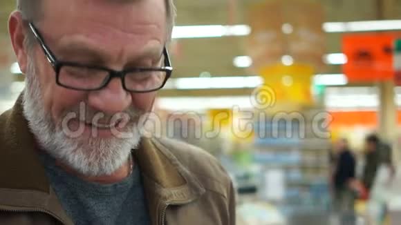 超市里的人微笑着用一个烦恼的钱包挥手灰色的胡须和眼镜可以看到皱纹视频的预览图