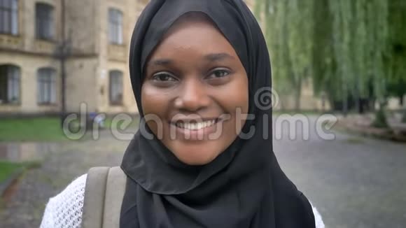 戴着头巾的非洲年轻穆斯林女人站在大学附近的公园里看着镜头微笑着开心快乐视频的预览图