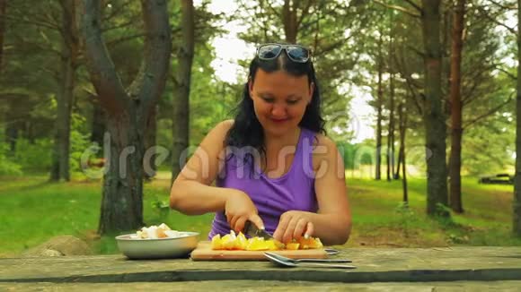 公园里的一个女人在野餐时把橘子切成块做水果沙拉视频的预览图