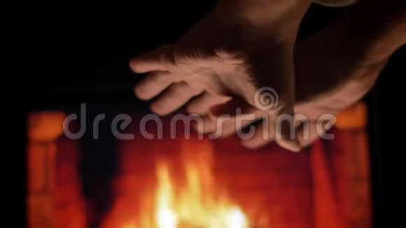 在寒冷的冬天在舒适的热壁炉和燃烧的木头前男性手在摩擦和温暖的特写镜头视频的预览图