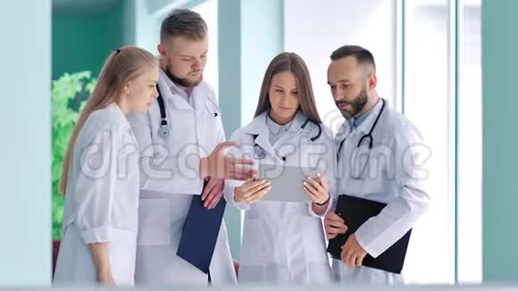 一群年轻医生用听诊器讨论看平板电脑屏幕的问题视频的预览图