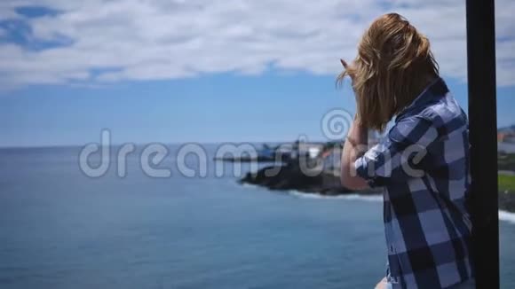 码头上的年轻女孩穿着衬衫和短裤看着大海视频的预览图