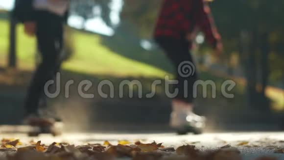 青少年滑板运动员在公园的落叶上骑滑板关注前景慢动作视频的预览图