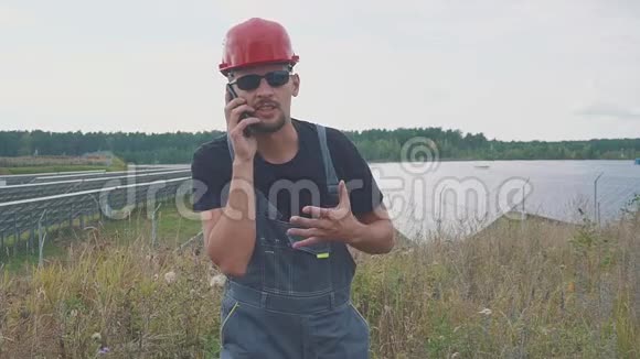 在太阳能发电站附近打电话的工人的肖像和手势发出积极的信号视频的预览图