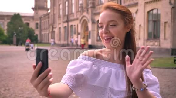 美丽的年轻姜女光着肩膀有视频聊天站在街上背景是建筑视频的预览图