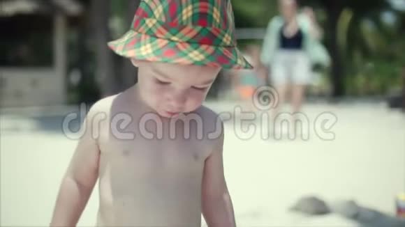 戴帽子的快乐男孩走在沙滩上背景是他的家人视频的预览图