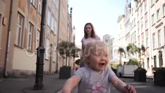 一个金发碧眼的小卷发女孩走在街上她母亲微笑着视频的预览图