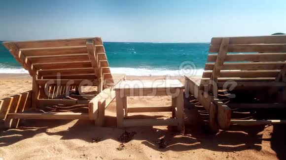 在废弃的海滩上拍摄两张木制日光浴床和一张小桌子的4视频的预览图