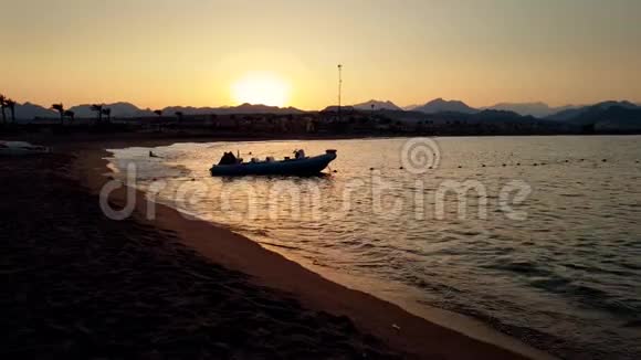 日落时分在沙滩旁漂浮的充气摩托艇4k视频视频的预览图