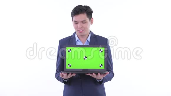 快乐的年轻亚洲商人一边思考一边展示笔记本电脑视频的预览图