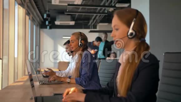 年轻友好的女接线员带耳机在呼叫中心工作视频的预览图