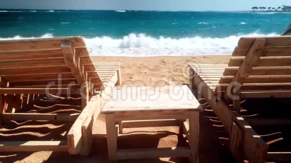 海滩上两个木制日光浴床的4K视频汹涌的海浪席卷海岸视频的预览图