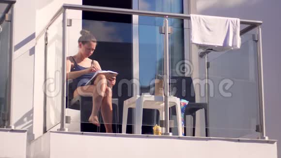 阳光明媚的天气女人在阳台上看书女孩阅读户外书籍视频的预览图