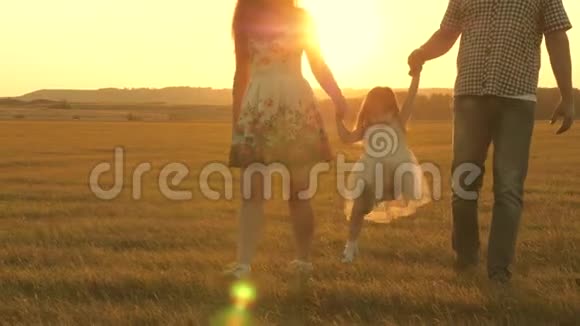 小女儿在太阳的背景下牵着爸爸和妈妈的手在公园里跳跃家庭观念孩子玩爸爸视频的预览图