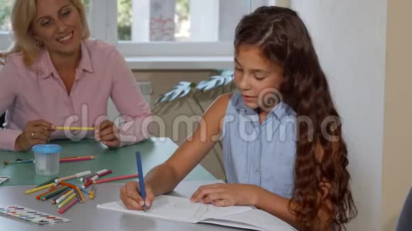 可爱的小女孩画画而她开朗的老师看着她视频的预览图