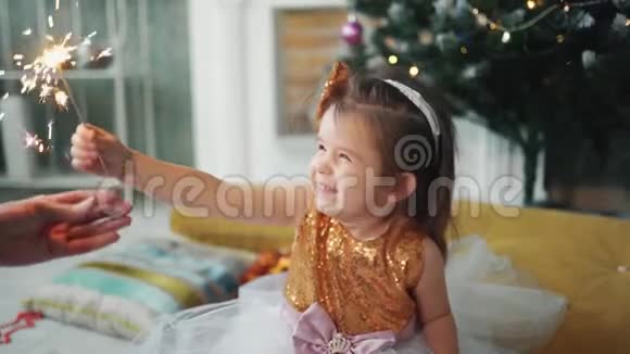 活泼开朗的小女孩正微笑着看着圣诞树脚下的星星视频的预览图
