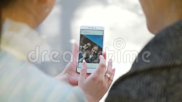 两位女士在白色智能手机上观看照片视频的预览图