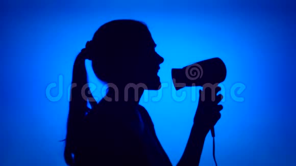 在吹风机里唱歌的女人的剪影女人在蓝底跳舞视频的预览图