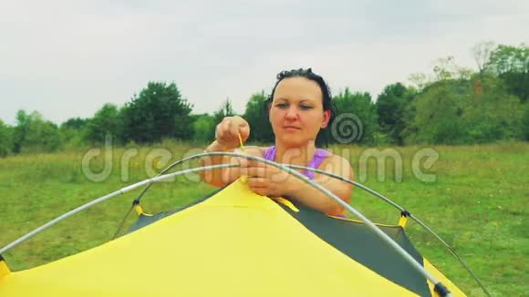 一个年轻的女人把帐篷的帐篷绑在拱门上系紧视频的预览图