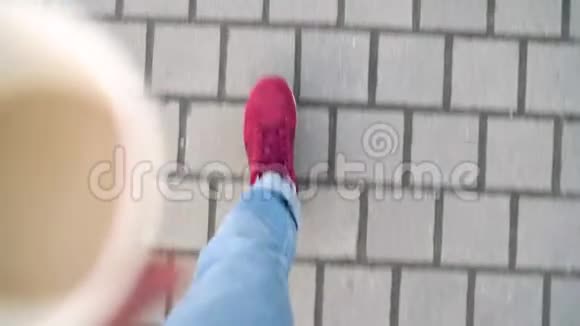 在人行道上行走的穿着红色运动鞋的男子腿的俯视图男人走路喝咖啡视频的预览图