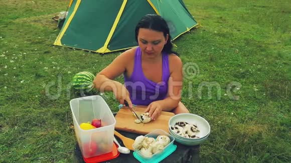 帐篷附近的一个林间空地上一个女人在树桩上剪了一个蘑菇蘑菇蘑菇作为一张桌子视频的预览图