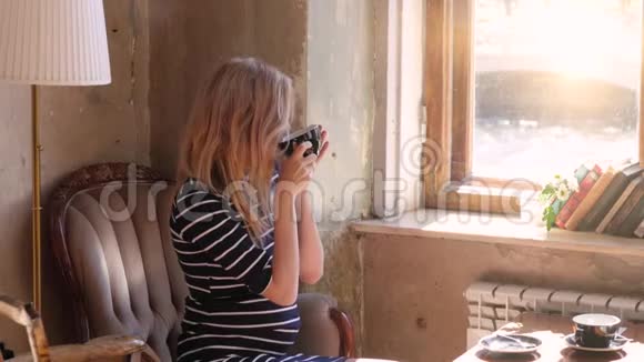 一个怀孕的金发女人坐在靠窗的咖啡馆喝茶美丽的扩散光图像视频的预览图