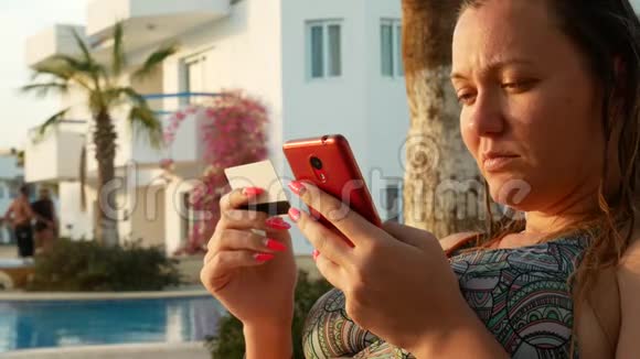 年轻女子用信用卡和红色智能手机上网购物视频的预览图