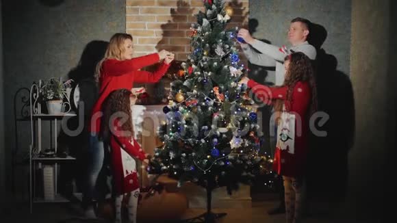 幸福的四口之家正在装饰圣诞树微笑着视频的预览图