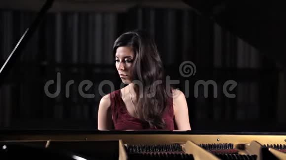 年轻漂亮的女士在弹钢琴为照相机摆姿势视频的预览图