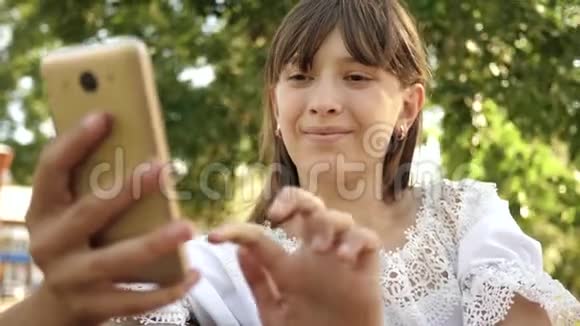 快乐女孩使用智能手机滚动页面在公园的网上商店在长凳上年轻的千禧年女性视频的预览图