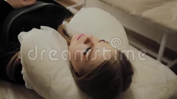 一个非常漂亮的女孩在美容院做一个层叠睫毛躺着等待睫毛上的干燥油漆视频的预览图