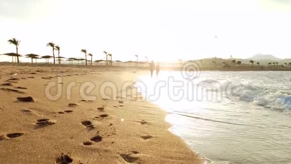 在日落时分一对情侣在沙滩上漫步视频的预览图