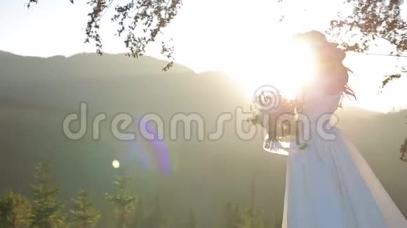 新娘婚礼在日落时在树和山的背景上举行婚礼花束太阳从外面下山视频的预览图