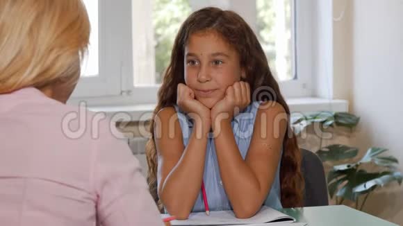 可爱的快乐女孩在课堂上和老师说话视频的预览图