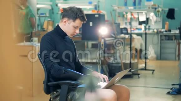 电脑实验室一个带假手的年轻人用笔记本电脑工作cyborg概念视频的预览图
