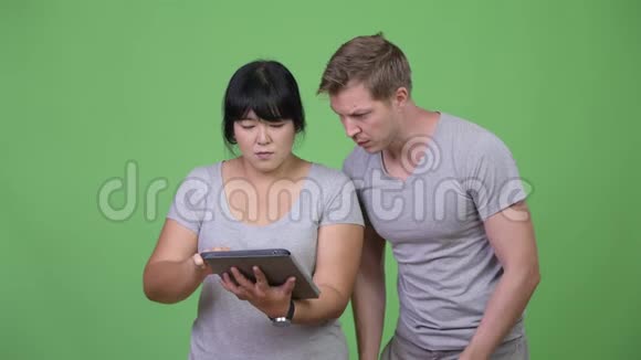 年轻的多民族夫妇使用数字平板电脑一起获得好消息视频的预览图